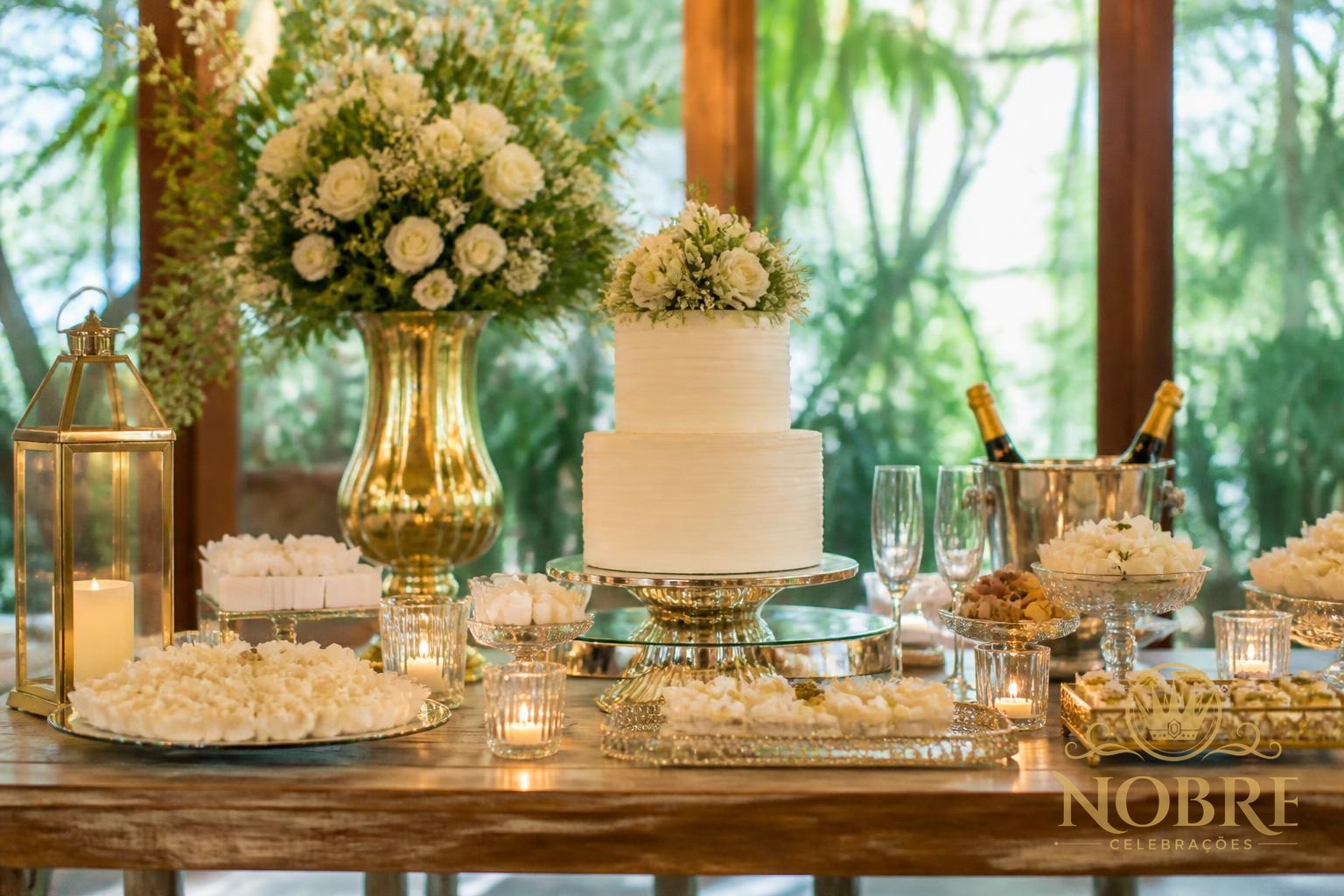Mesa principal de bodas com bolo elegante, flores naturais, velas e doces finos em tons champagne e dourado discreto